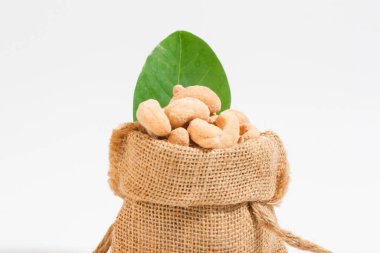 Atıştırmalık olarak kaju. Çuvallara konur ve tahta kaşık alanına yerleştirilir. Beyaz arka plan.. 