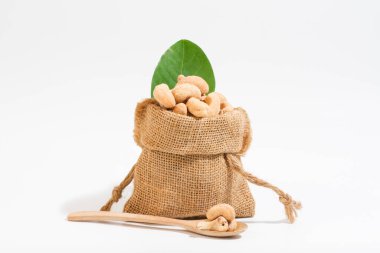 Atıştırmalık olarak kaju. Çuvallara konur ve tahta kaşık alanına yerleştirilir. Beyaz arka plan.. 