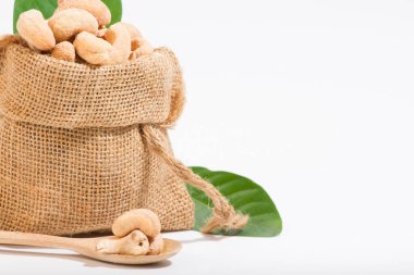 Atıştırmalık olarak kaju. Çuvallara konur ve tahta kaşık alanına yerleştirilir. Beyaz arka plan.. 