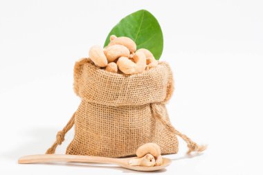 Atıştırmalık olarak kaju. Çuvallara konur ve tahta kaşık alanına yerleştirilir. Beyaz arka plan.. 