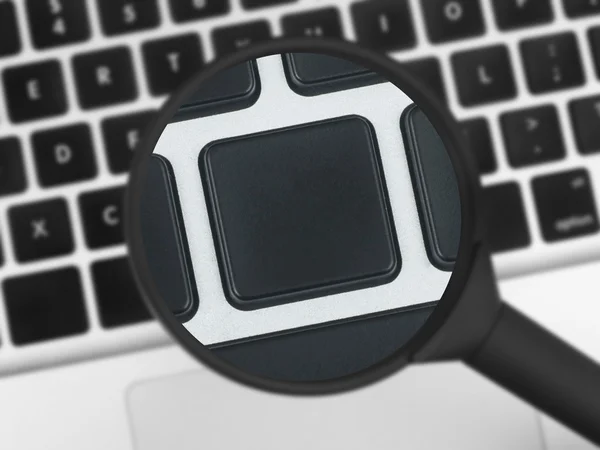 Magnifying glass over a laptop keyboard — Stock Photo, Image