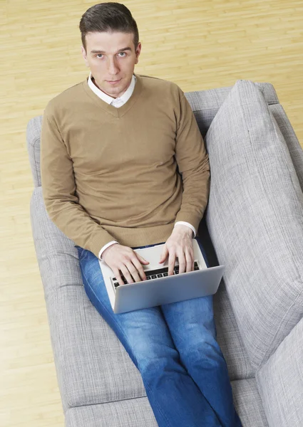 Άνθρωπος στον καναπέ με φορητό υπολογιστή — Φωτογραφία Αρχείου