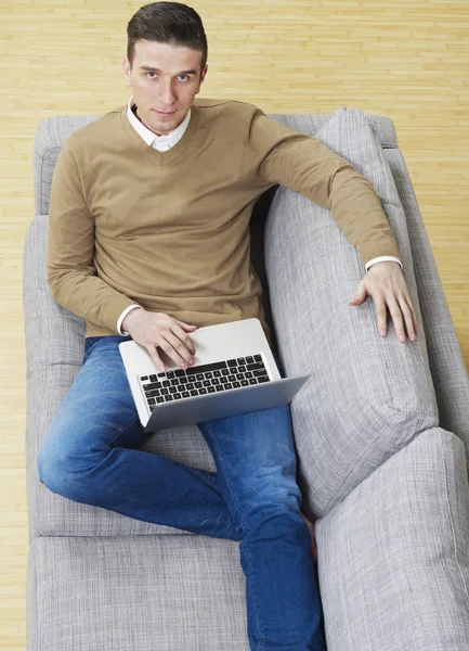 Άνθρωπος με φορητό υπολογιστή στον καναπέ — Φωτογραφία Αρχείου