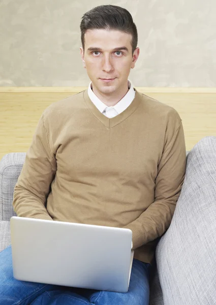 Homme avec ordinateur portable regardant la caméra — Photo