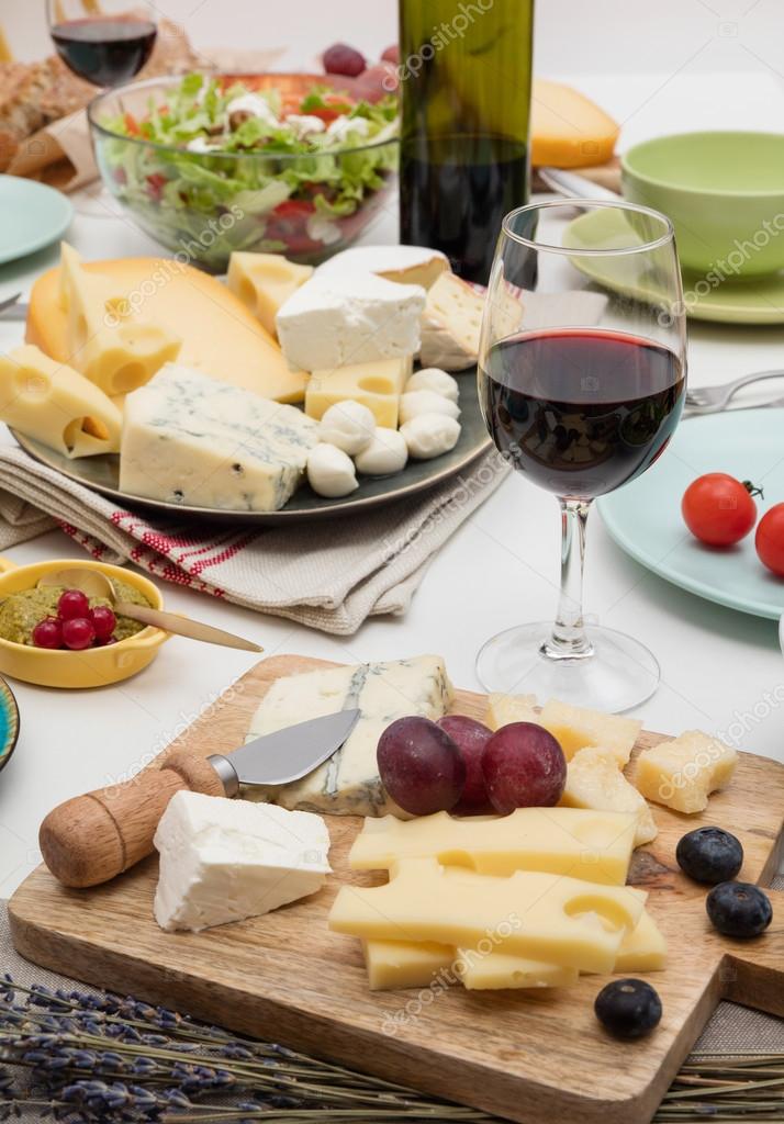 Cheese and Fruits Assortment on Cutting Board with Red, White Wine on  Wooden Background. Stock Photo by annapustynnikova