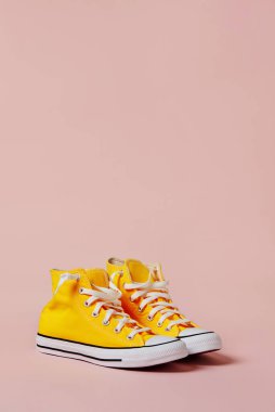 Pembe arka planda sarı tuval ayakkabılar