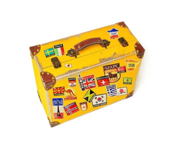 Yellow luggage with country stickers on white background