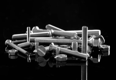 Siyah arka planda metal cıvatalar ve fındıklar