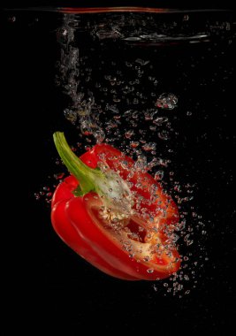 Kırmızı biber siyah arka planda suya sıçrıyor.