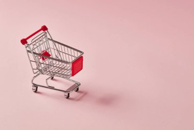 Pembe arka planda boş alışveriş arabası