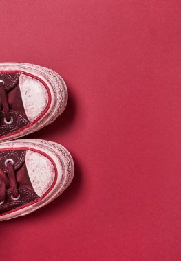 Kırmızı arkaplanda kullanılmış tuval ayakkabılar