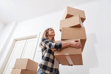 Yeni bir dairede karton kutuları olan genç bir kadın.