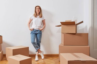 Karton kutuları olan, taşınma konsepti olan yeni bir dairede genç bir kadın.