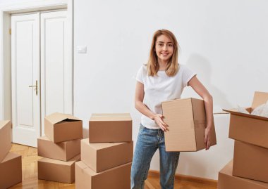 Yeni bir dairede karton kutuları olan genç bir kadın.