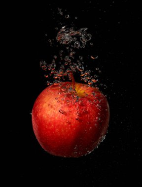 Siyah arkaplanda suya düşen elma