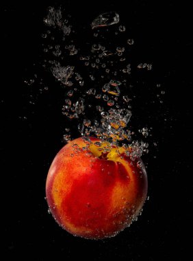 Şeftali siyah arkaplanda suya sıçrıyor