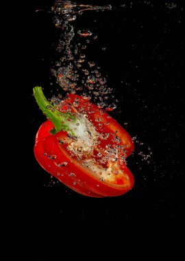 Kırmızı biber siyah arka planda suya sıçrıyor.