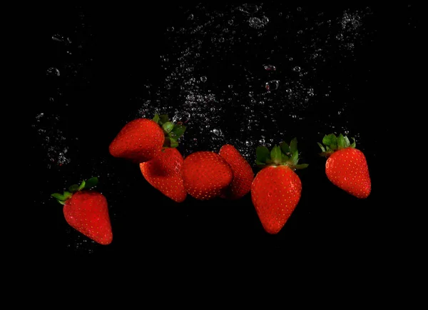 Erdbeere Planscht Wasser Auf Schwarzem Hintergrund — Stockfoto