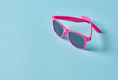 Mavi arka planda yaz pembe güneş gözlükleri