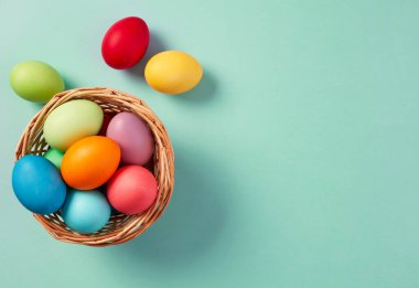 Renkli paskalya yumurtaları ve pastel arka planda Hasır sepet