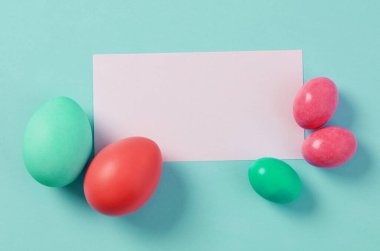 Mavi arka planda renkli paskalya yumurtaları olan boş bir kart.