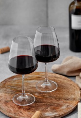 Ahşap servis tahtasının üzerinde iki güzel kadeh kırmızı şarap.