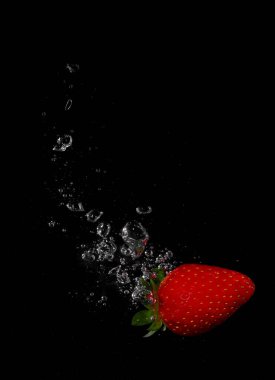 Suda taze çilek sıçraması, siyah üzerine izole edilmiş.
