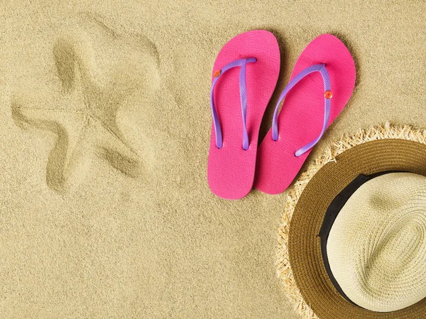 Pantofle a klobouk na písku — Stock fotografie