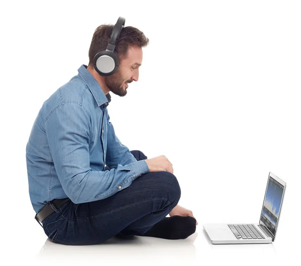 Man med hörlurar och laptop — Stockfoto