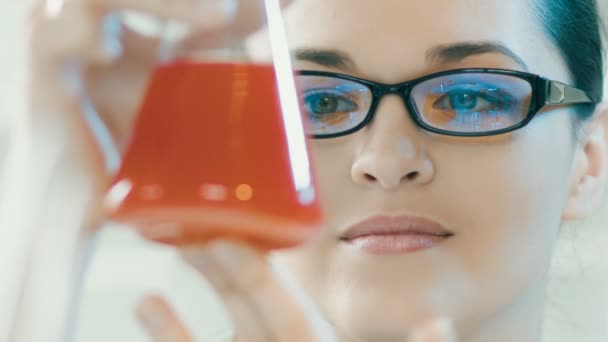 Vrouw kijken naar kolf in een laboratorium — Stockvideo