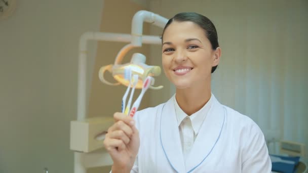 Médico dentista sosteniendo cepillos de dientes — Vídeos de Stock