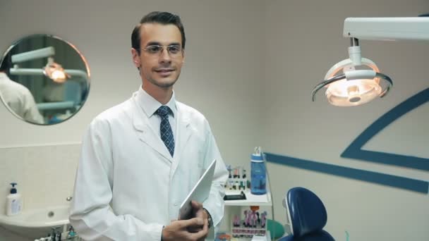 Dentista sorridente con tablet presso la clinica dentale — Video Stock