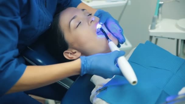 Dentis zet tandvullingen met blauw licht — Stockvideo