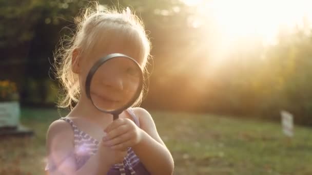 Ragazza guardando attraverso una lente di ingrandimento al tramonto — Video Stock