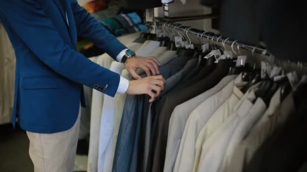 Мужчина выбирает костюм в магазине одежды — стоковое видео