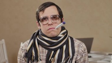 Ağzında termometreyle atkı takan komik bir adam.