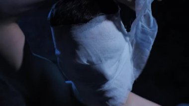 Adam başındaki bandajları çıkarıyor.