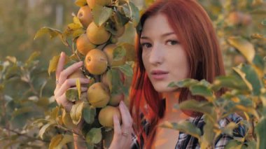 Elma ağacı dalı tutan tatlı kızıl saçlı kadın.