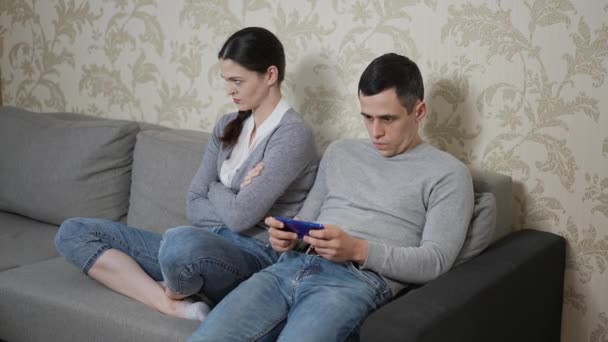 El hombre juega juegos en el teléfono inteligente y la esposa está insatisfecha — Vídeos de Stock