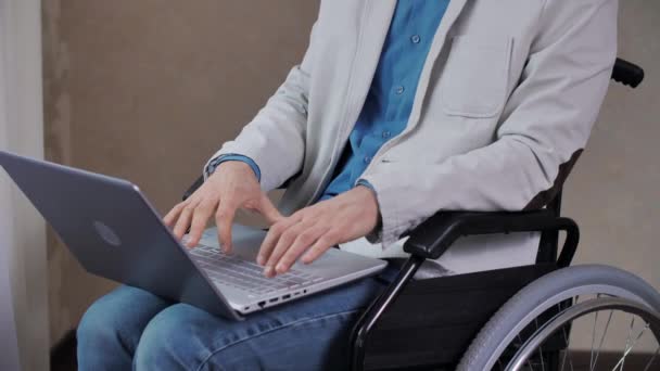 Mozgássérült férfi tolószékben, aki laptopon dolgozik — Stock videók