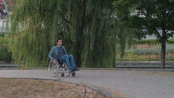Чоловік у інвалідному візку, що їде по вулиці — стокове відео