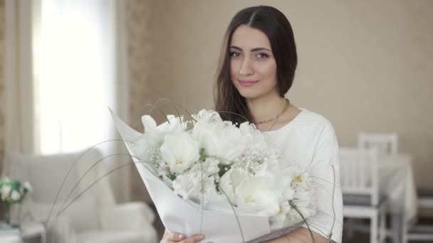 Hermosa mujer con flores blancas en casa — Vídeos de Stock