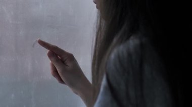 Pencereye kalp çizen bir kadın