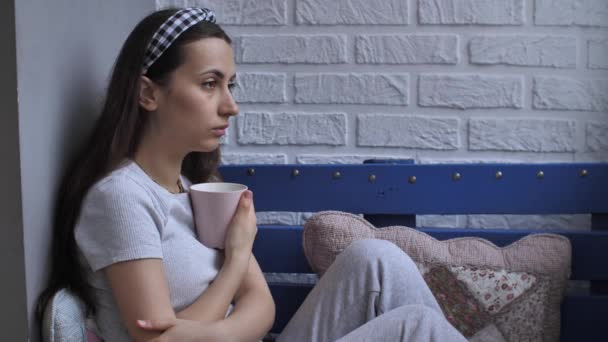 Triste femme assise sur le canapé avec tasse — Video