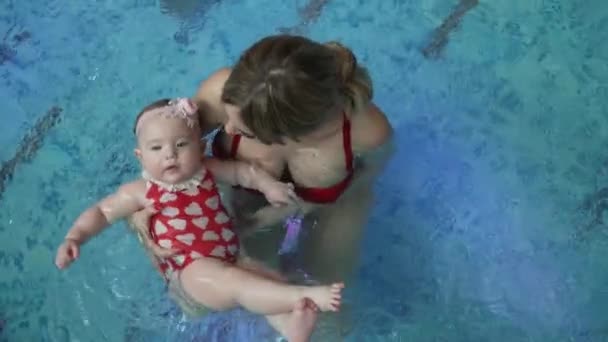 Klein meisje met haar moeder in het zwembad — Stockvideo