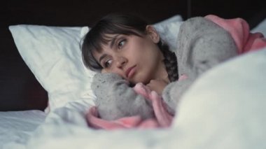 Üzgün kadın yatakta yatıyor.