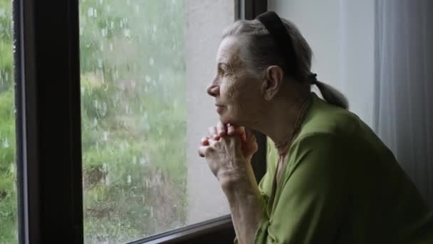 Alte Frau blickt aus dem Fenster — Stockvideo
