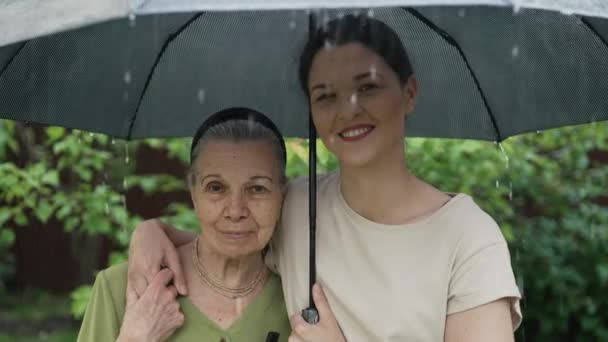 Grootmoeder en meisje onder paraplu in de regen — Stockvideo