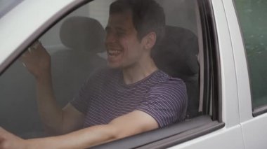 Neşeli adam araba sürerken ot içer.