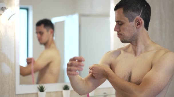 El hombre frente a un espejo mide bíceps — Vídeos de Stock